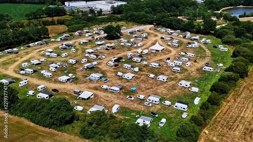 Aerial view of a large caravan park with numerous campers and trailers parked on a grassy field surrounded by trees in Nantes, Pays de la Loire, France.