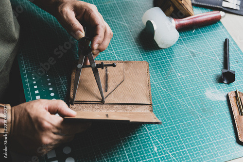 Artisan marking lines on natural leather using a leatherworker's compass.