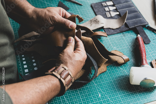 Leather artisan checking the softness and quality of a piece of leather with his hands.