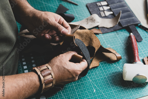 Leather artisan checking the softness and quality of a piece of leather with his hands.