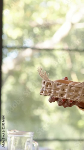 Vertical video: Bringing woman's sweater-clad arm placing wicker-basket on table for meal