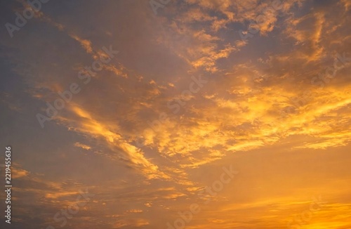 Soft golden clouds drift across the evening sky, illuminated by the warm glow of a stunning sunset.
