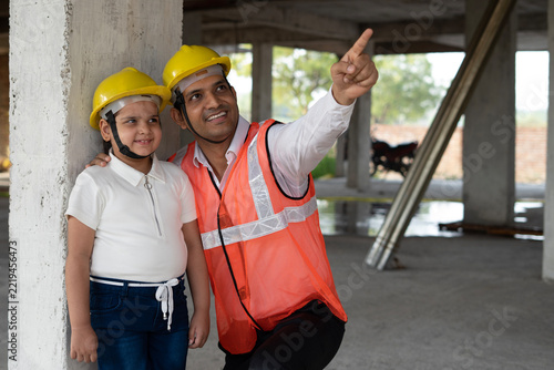 Indian little girl visits construction site. Engineer manager working with her like team and reviewing and analyzing the work in progress. The little girl takes the tour of builder construction