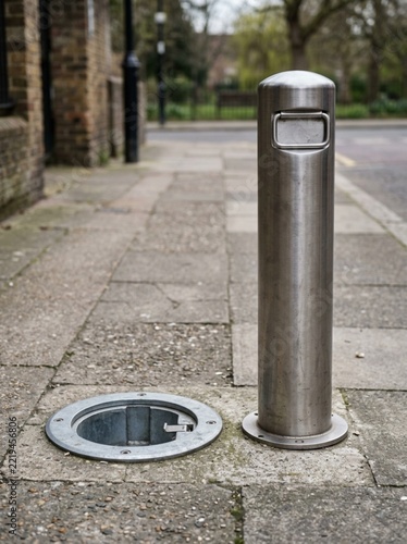 Stainless Steel Retractable Security Bollard Installed on Urban Sidewalk, Removable Traffic Barrier Post for Pedestrian Safety and Vehicle Access Control in City Street Infrastructure Environment
