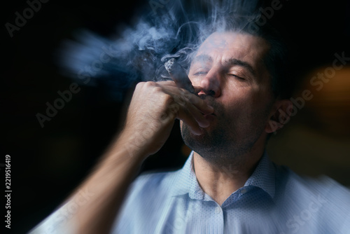 portrait of hansome man smoking cigar in a lounge bar with motion blur effect