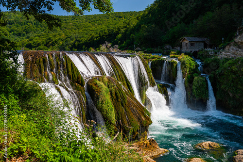 Wide moss-covered Strbacki Buk waterfall with traditional watermill, Una River, Bosnia