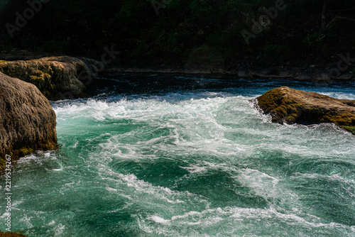 Turbulent turquoise rapids swirling between moss-covered rocks, Una River, Bosnia
