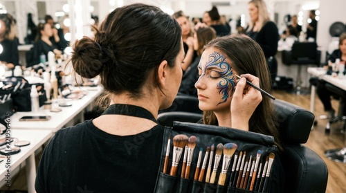 A makeup artist applies detailed blue and gold face paint with a fine