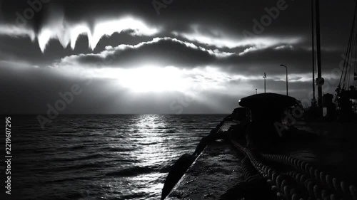 Dramatic black and white landscape of a seaside pier at dusk with atmospheric clouds and ocean waters