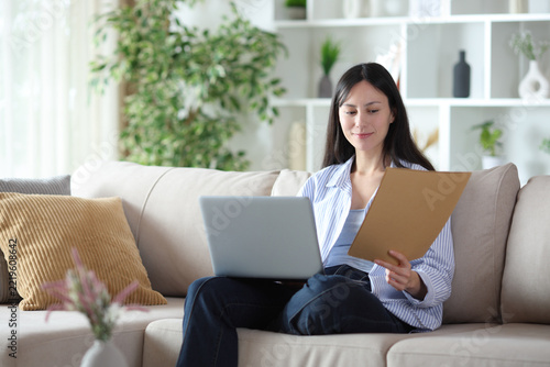 Asian woman working online at home checking document