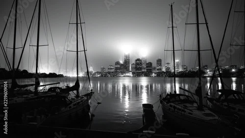 Black and White Serene Night View of Sailboats Docked with City Lights Reflected in Water