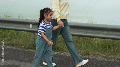 slow motion of mother and preschool child girl holding hand and walking on a road on mountain in the morning