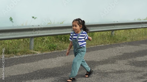 slow motion of preschool child girl walking on a road on mountain in the morning