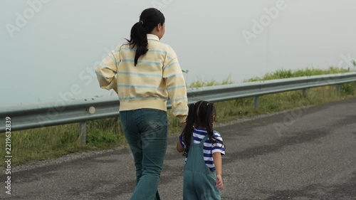 slow motion of mother and preschool child girl holding hand and running on a road on mountain in the morning