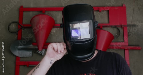 Bearded craftsman in sunglasses lowering protective welding shield before work