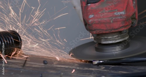 Metal cutting process with angle grinder rotating disc throwing sparks close up
