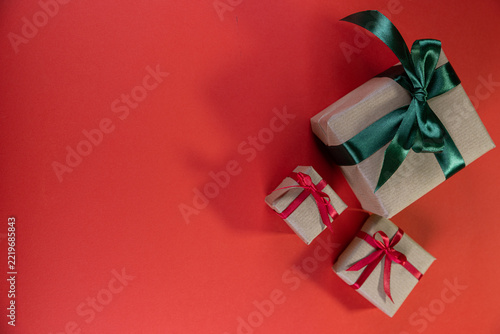 Three presents wrapped in brown paper with bows against a red background