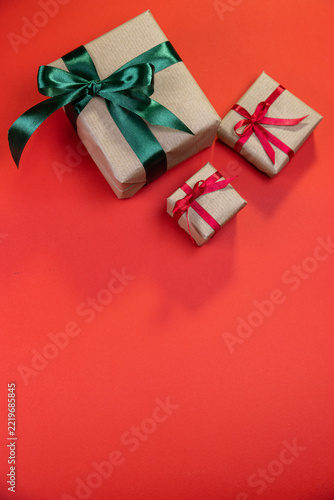 Three presents wrapped in brown paper with bows against a red background
