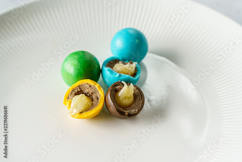 Round chocolate bonbon with colored chocolate and caramel inside.