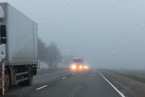 Truck on a country road in the thick fog. Poor visibility conditions on the road.
