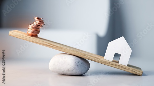 House model balanced against stacked coins on a wooden seesaw representing real estate investment and financial stability