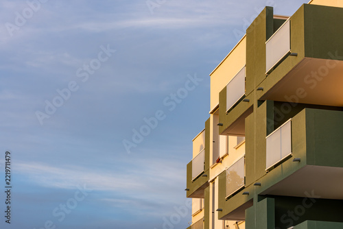 Green and beige building balcony with white railing and ground floor entrance