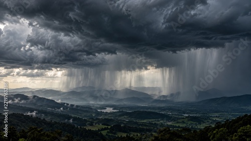 Dense Charcoal Storm Clouds with Distant Rain Curtains across a Wide Sky