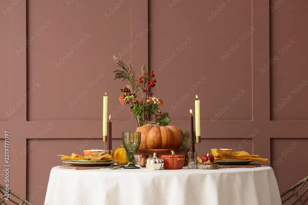 Fototapeta premium Thanksgiving dinner table setting, autumn harvest celebration and holiday hospitality with pumpkin centerpiece and candles in a cozy dining room