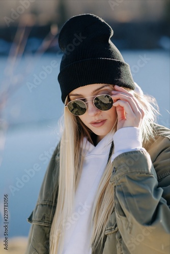 Young Blonde Woman Wearing Beanie and Sunglasses in Casual Winter Streetwear