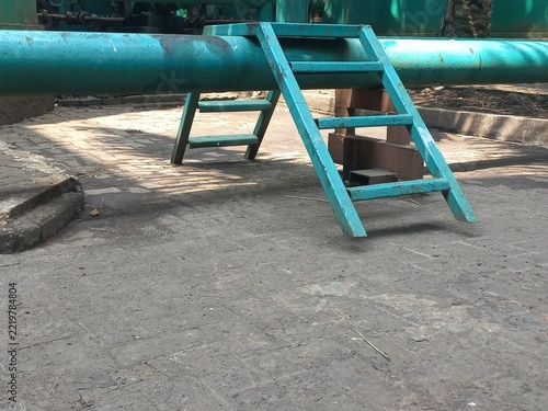 Green Metal Crossover Ladder Over Industrial Pipeline.