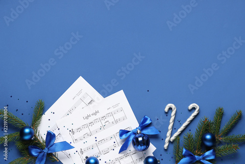 Composition with music sheets, fir branches and Christmas decorations on blue...
