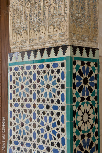 Colorful geometric Moorish tiles below carved plaster decoration