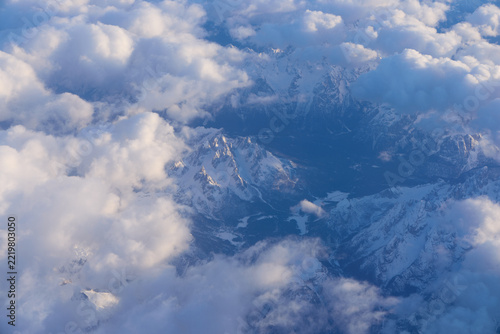 Aerial view of snowy mountain valleys under fluffy clouds