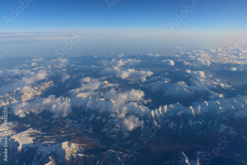 Aerial panorama of snowy mountain ranges under clear blue sky