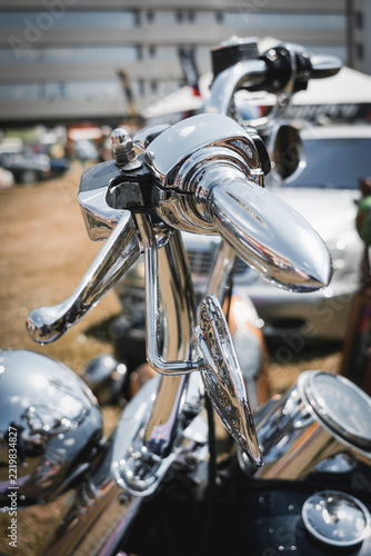 Polished chrome motorcycle handlebars and controls at a vintage motorcycle show, highlighting reflective metal details.jpg