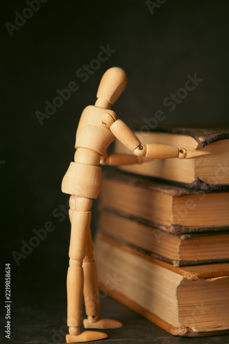 Wooden mannequin and books on black background, closeup