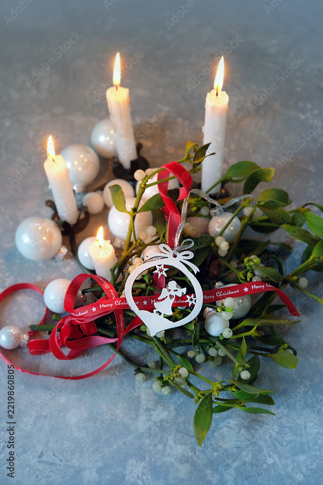 Fototapeta premium Christmas background. candles, decor with angel, christmas balls, ribbons, mistletoe branches on table. Composition for Christmas, Advent, Yule, New Year holidays, festive winter season