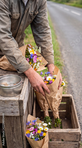 Farmer Wrapping Wildflower Bouquets in Paper at Rustic Roadside Stand