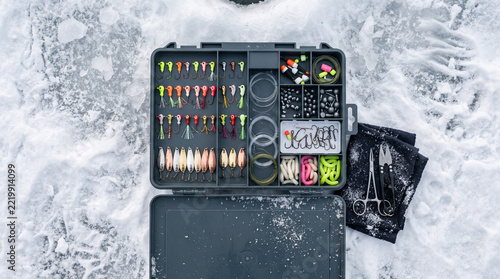 Ice fishing tackle box open with various lures and accessories  