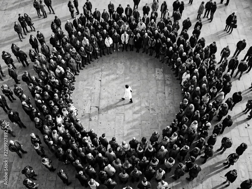 Person walking through a large crowd forming a human circle in public
