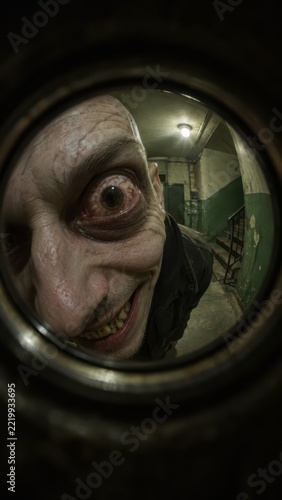 Distorted pale face fills a circular view of the dim stairwell