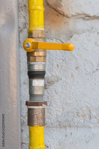 Yellow metal pipes and fittings demonstrate the connection of gas pipelines in industrial infrastructure and emphasize energy transportation technology. vertical photo
