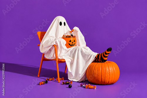 Funny Halloween Ghost Relaxing with a Bucket Full of Trick or Treat Candy