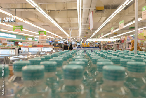 Rows of bottled water neatly arranged under bright fluorescent lights in a modern supermarket aisle