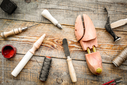 Clobber tools pattern. Wooden last, hammer, awl, knife, thread on wooden background top view