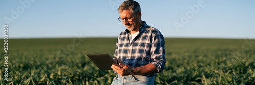 Farmer using tablet in crop field for agriculture management and data monitoring background for farm business and agtech design
