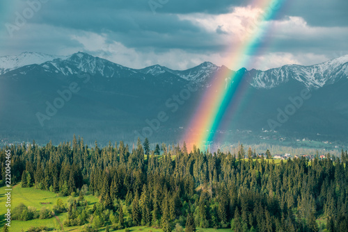 Majestic panoramic view of the Tatra Mountains landscape featuring snow-capped peaks, colorful forests, and picturesque valleys under a dramatic sky. Beautiful scenic nature and wilderness background