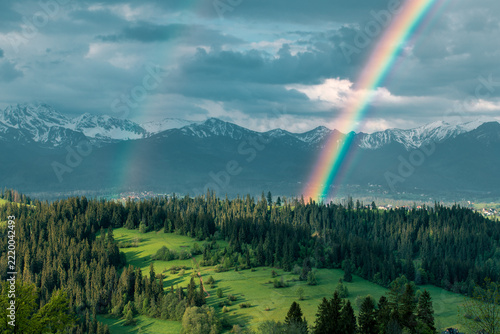Majestic panoramic view of the Tatra Mountains landscape featuring snow-capped peaks, colorful forests, and picturesque valleys under a dramatic sky. Beautiful scenic nature and wilderness background