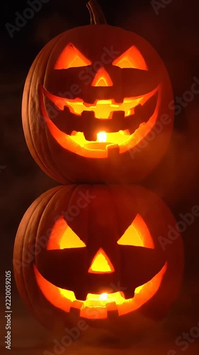 Scary pumpkins glow with warm light and display carved faces on their surfaces