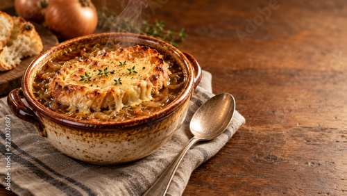 Rustic onion soup with golden cheese toast beside a plain spoon and linen